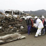 Rescue workers carry the body of a victim at a village destroyed by the earthquake and tsunami in Rikuzentakata