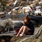A woman cries while sitting on a road amid the destroyed city of Natori, Miyagi Prefecture in northern Japan
