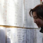 A survivor looks at a board showing names of other survivors at a shelter in a village ruined by an 8.9 magnitude earthquake and tsunami, in Rikuzentakata in Iwate prefecture, northeast Japan