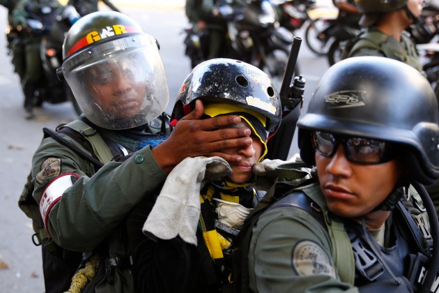 National guard tries to cover the face of a detainee to avoid being photographed during a protest against Nicolas Maduro's government in Caracas