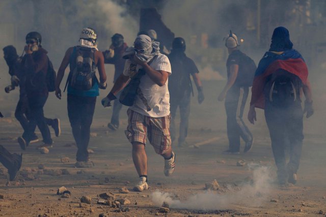 Anti-government protesters run away from teargas during a protest against Nicolas Maduro's government at Altamira square in Caracas