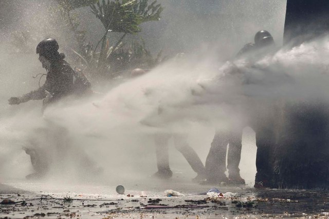Anti-government protesters are hit by police water cannon during a demonstration against Maduro's government in Caracas