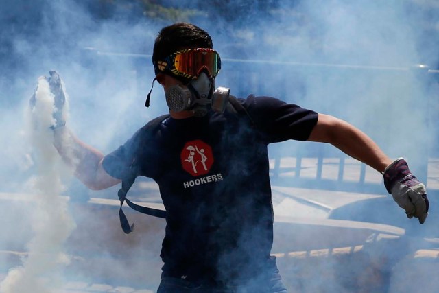 An anti-government protester throws a teargas canister back at the police in Caracas