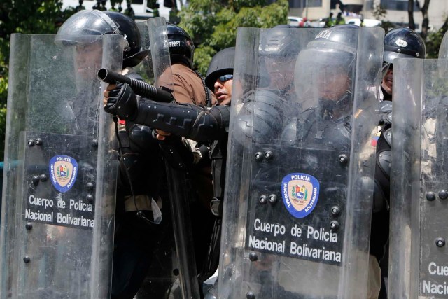 A riot police officer prepares to fire teargas at anti-government protesters in Caracas