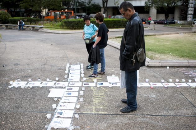 Un hombre observa en la Plaza Altamira una cruz hecha con los retratos de todas las personas muertas durante las protestas que desde hace más de un mes  (Foto EFE)