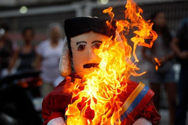 Anti-government protesters burn an effigy depicting Venezuela's President Nicolas Maduro in Caracas