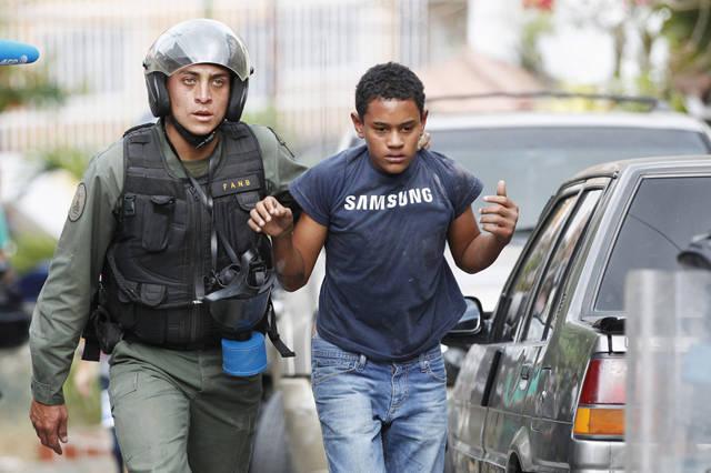 An anti-government protester is detained by national guard after clash with guard at the end of a march in Caracas