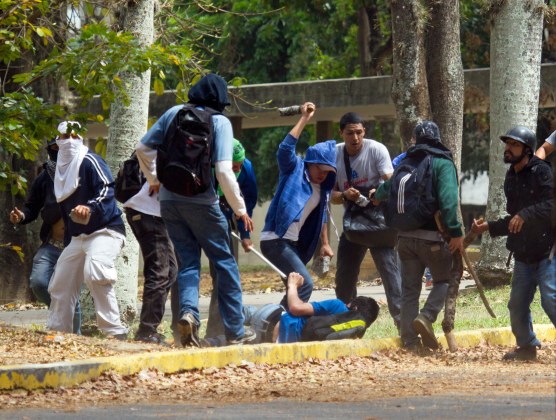 Un estudiante opositor, tendido en el suelo, es atacado por un grupo pro gubernamental dentro de la Universidad de Venezuela, durante una manifestación contra el gobierno el jueves 3 de abril de 2014 en Caracas, Venezuela. (Foto AP/Fernando Llano)