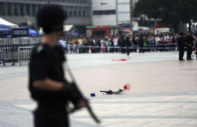 Un policía armado (frontal) está de guardia cerca de una placa de policía (C) que se quedó en el suelo después de una pelea entre un policía y un atacante, en una estación de tren de Guangzhou, provincia de Guangdong /  Stringer  / Reuters