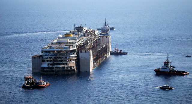 Tugboats drag the cruise liner Costa Concordia as they leave Giglio Island