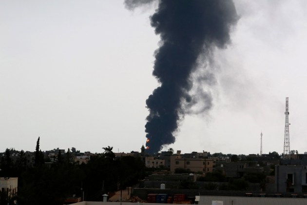 Plumes of smoke rise in the sky after a rocket hit a fuel storage tank near the airport road in Tripoli, during clashes between rival militias