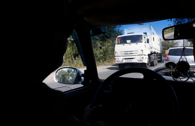 A truck of a Russian convoy carrying humanitarian aid for Ukraine is seen through a car window, as it drives in the direction of the Ukrainian border near the town of Donetsk, in Russia's Rostov Region