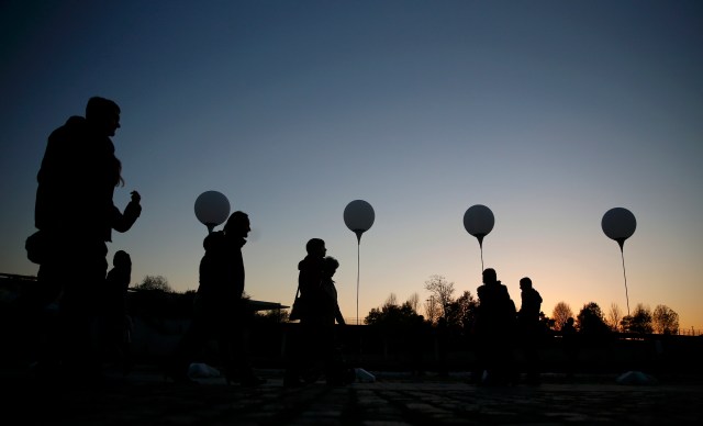People walk under stands with balloons along Spree river in Berlin