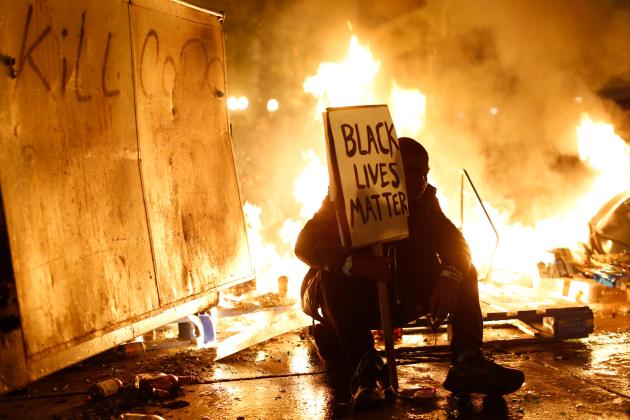 Demonstrator sits in front of a street fire during a demonstration following the grand jury decision in the Ferguson, Missouri shooting of Michael Brown, in Oakland, California
