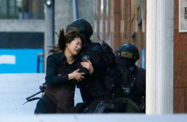 A hostage runs towards a police officer outside Lindt cafe, where other hostages are being held, in Martin Place in central Sydne