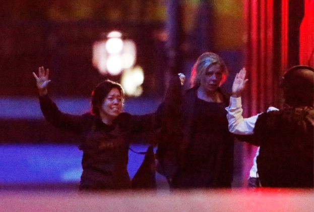 Hostages run towards a police officer (R) near Lindt Cafe, at Martin Place in central Sydney
