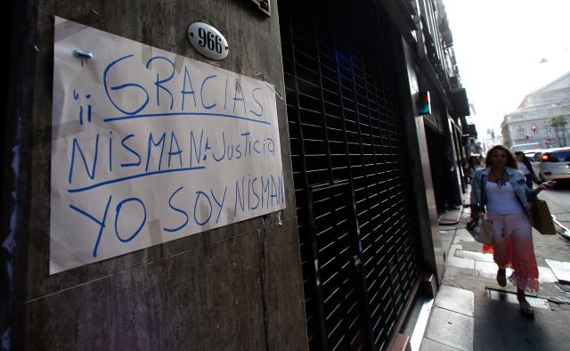 A woman walks past a sign that reads "Thanks Nisman. Justice. I am Nisman" in Buenos Aires