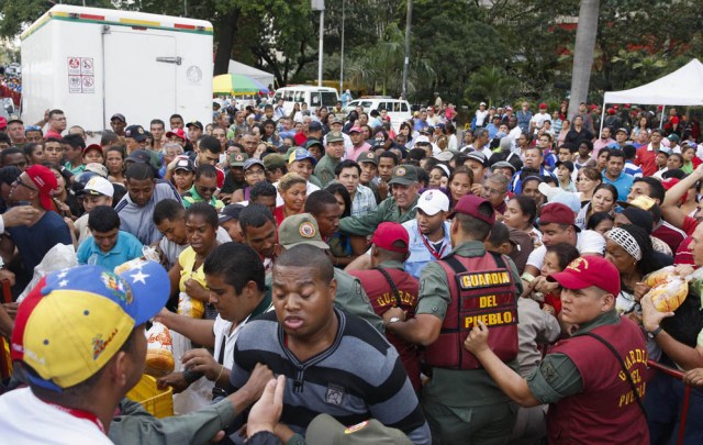 Venezuelan soldiers try to control the crowd as people attempt to buy chickens at a Mega-Mercal, a subsidized state-run street market, in Caracas