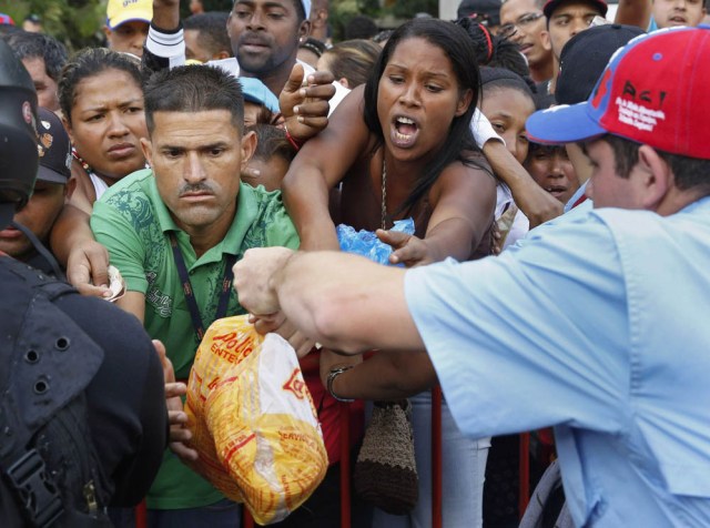People crowd together in an attempt to buy chickens at a Mega-Mercal, a subsidized state-run street market, in Caracas