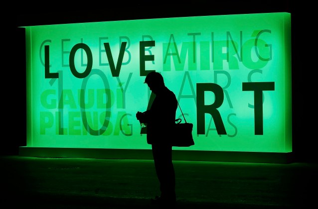 A man checks his mobile phone in front of an illuminated billboard at the Mobile World Congress in Barcelona