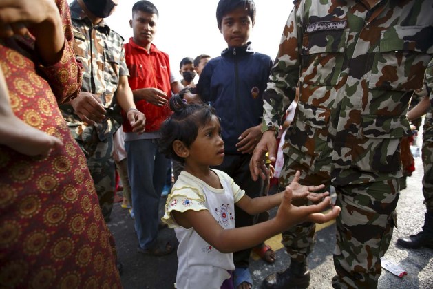 Girl spreading her arms asks soldiers for food near a makeshift shelter after the April 25 earthquake in Kathmandu