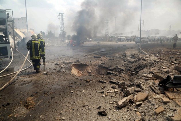 Civil defense members rush to put out a fire at a site hit by what activists said was a barrel bomb dropped by forces loyal to Syria's President Bashar al-Assad, followed by shelling at a bus station in Jisr al-Hajj roundabout in Aleppo