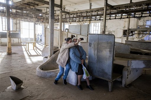 En esta imagen del 7 de julio de 2015, Belén Gadea, a la izquierda, se hace una foto con su abuela Ivis Saldaña en el matadero de la histórica planta de procesamiento de carne Anglo en Fray Bentos, Uruguay. El esposo y el hijo de Saldaña trabajaron en la fábrica. (AP Foto/Matilde Campodonico)