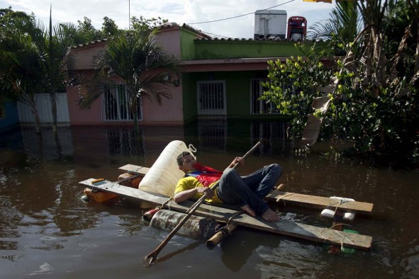 A man paddles a makeshift boat along a flooded street in Guasdualito