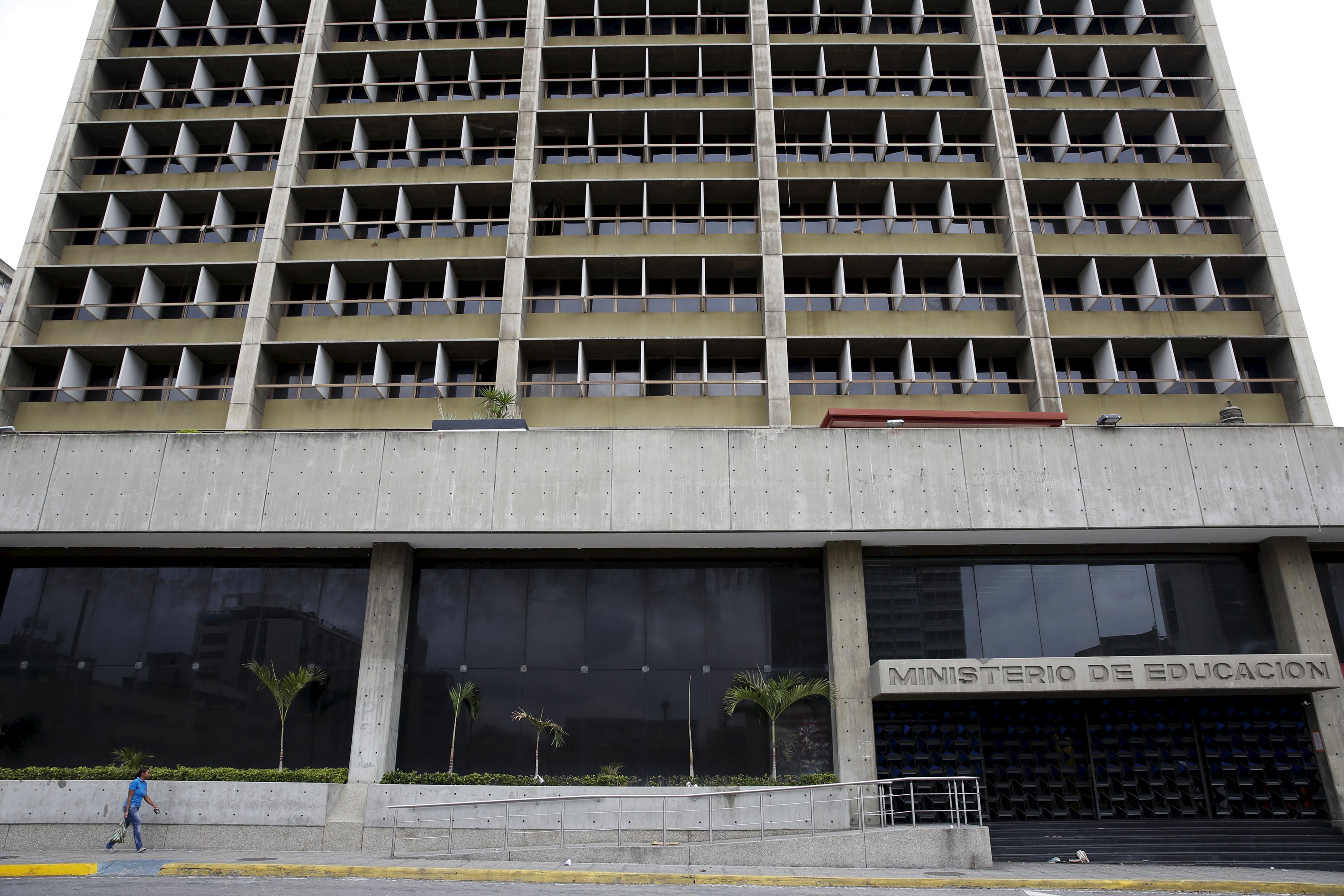 A woman walks past the closed entrance of the Ministry of Education building in Caracas April 22, 2016. REUTERS/Carlos Garcia Rawlins