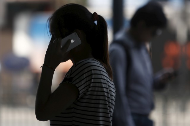 Una mujer hablando por un celular iPhone, mientras camina por una calle en el centro de Shanghái. Foto: Reuters