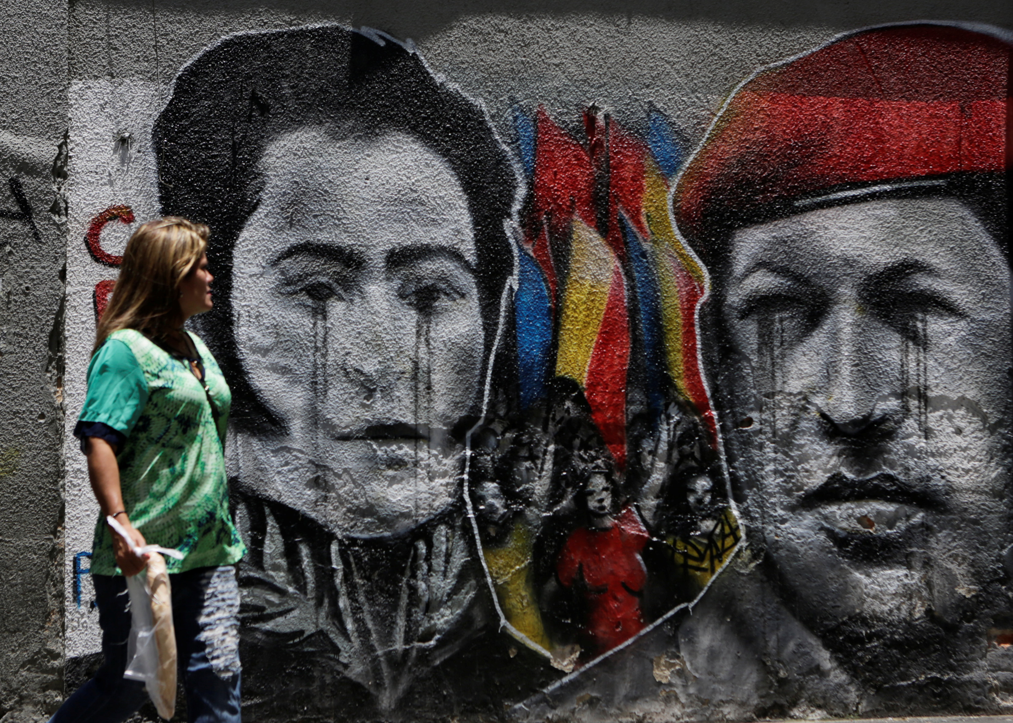 A woman looks at a mural depicting Venezuela's national hero Simon Bolivar (L) and Venezuela's late president Hugo Chavez in downtown Caracas, Venezuela September 18, 2016. REUTERS/Henry Romero FOR EDITORIAL USE ONLY. NO RESALES. NO ARCHIVES.