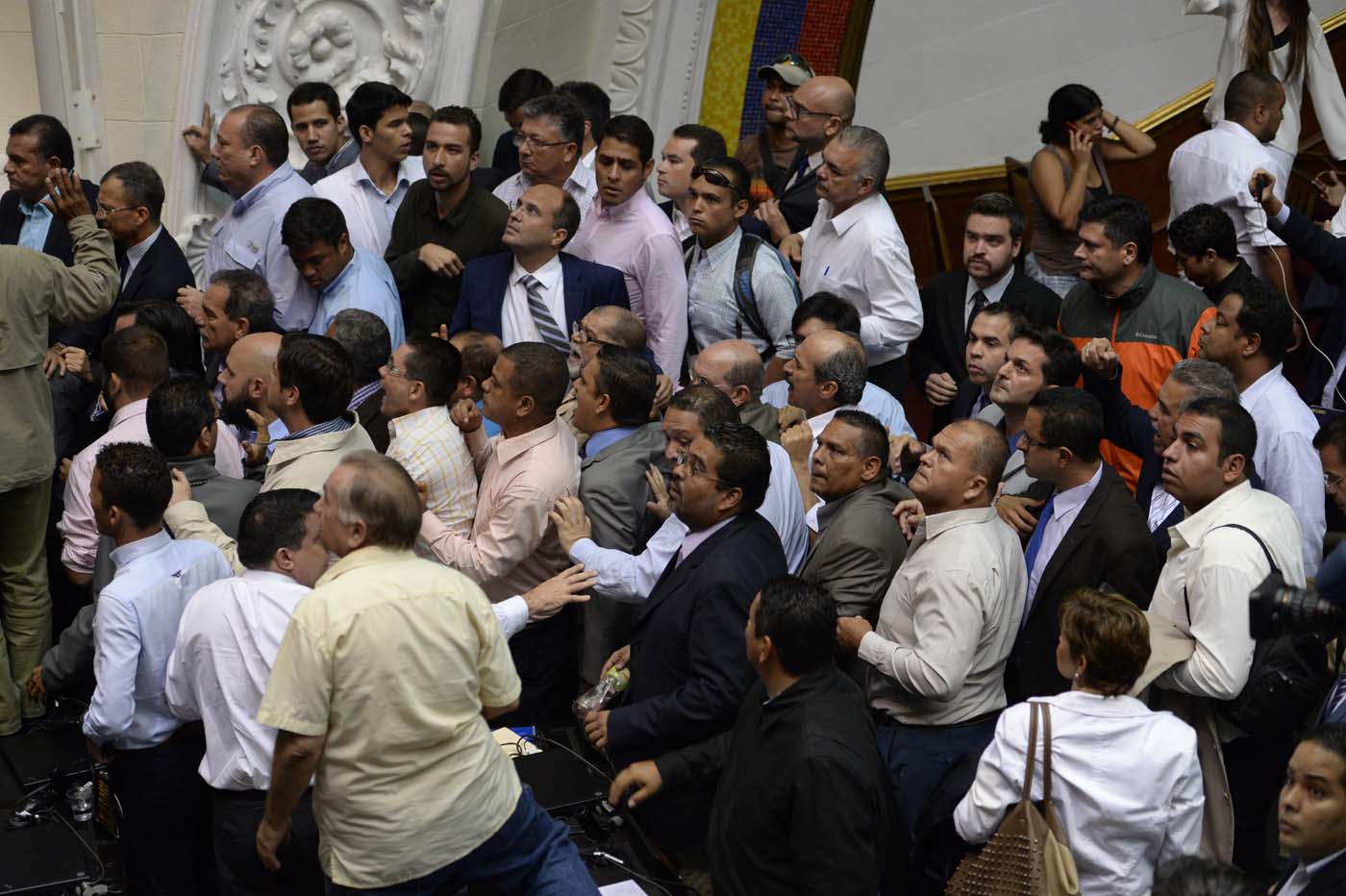 Members of the National Assembly react as supporters of Venezuelan President Nicolas Maduro force their way during an extraordinary session called by opposition leaders, in Caracas on October 23, 2016. The opposition Democratic Unity Movement (MUD) called a Parliamentary session to debate putting President Nicolas Maduro on trial to "restore democracy" in an emergency session that descended into chaos as supporters of the leftist leader briefly seized the chamber. / AFP PHOTO / FEDERICO PARRA