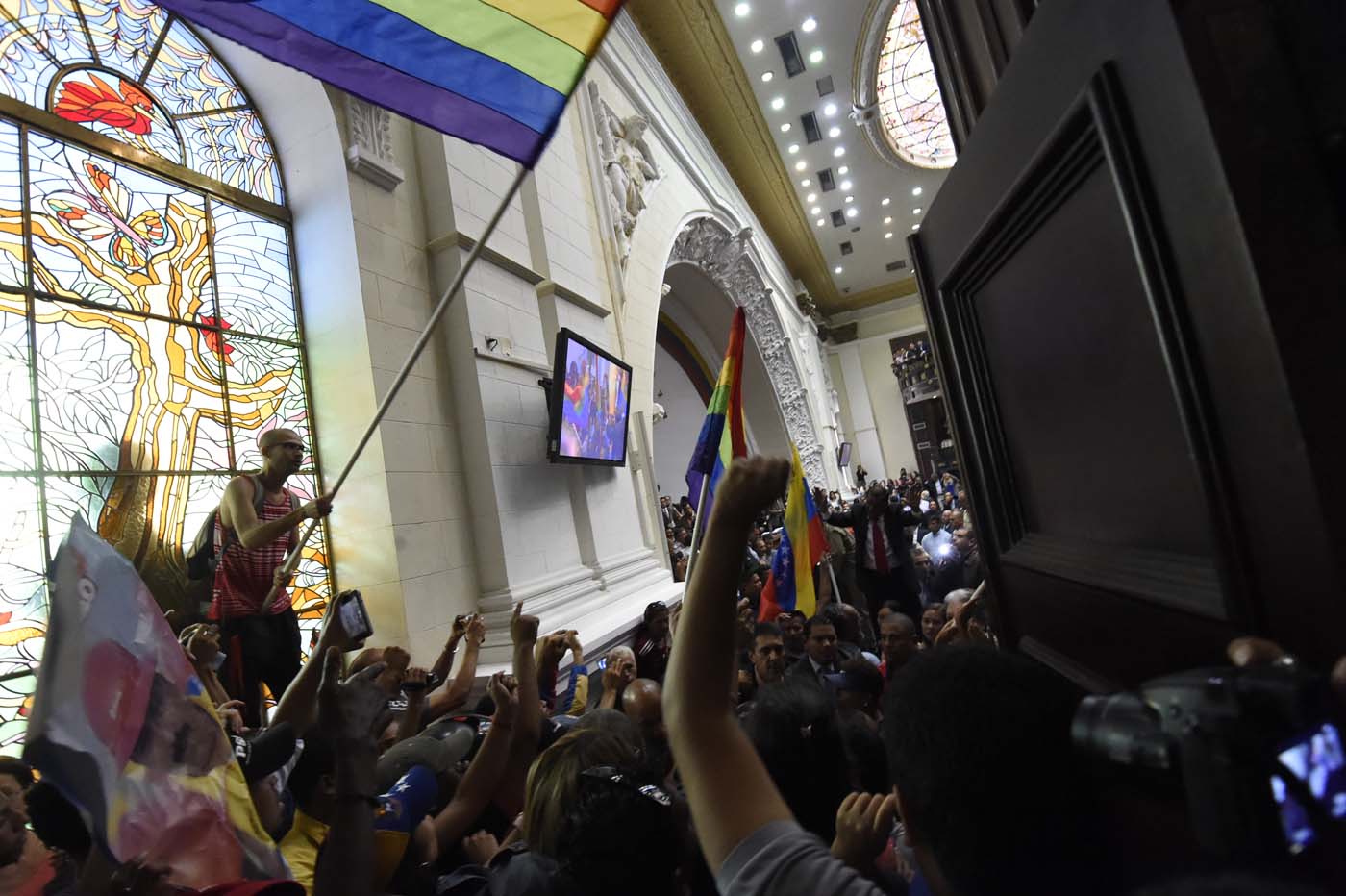 Supporters of Venezuelan President Nicolas Maduro force their way to the National Assembly during an extraoridinary session called by opposition leaders, in Caracas on October 23, 2016. The Democratic Unity Movement(MUD), opposite to Nicolas Maduro's government called a Parliamentary session to discuss restructuring of the Boliviarian Republic of Venezuela's Constitution, the constitutional order and democracy as main issues. Demonstrators outside the building forced their entrance to interrupt the debate and the session was suspended. / AFP PHOTO / JUAN BARRETO