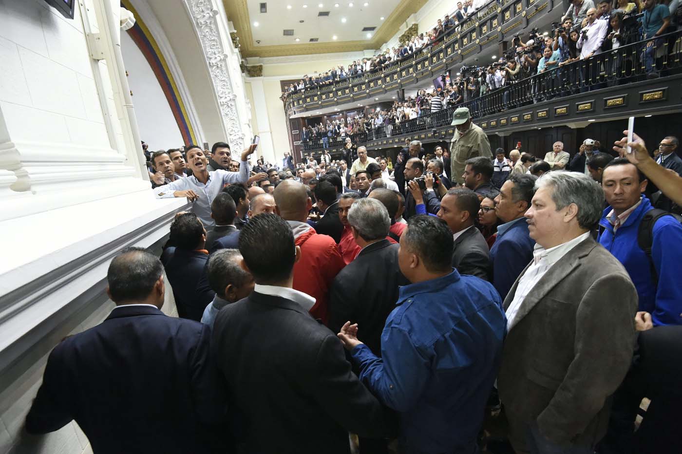 Members of the National Assembly react as supporters of Venezuelan President Nicolas Maduro force their way during an extraordinary session called by opposition leaders, in Caracas on October 23, 2016. The Democratic Unity Movement(MUD), opposite to Nicolas Maduro's government called a Parliamentary session to discuss restructuring of the Boliviarian Republic of Venezuela's Constitution, the constitutional order and democracy as main issues. Demonstrators outside the building forced their entrance to interrupt the debate and the session was suspended. / AFP PHOTO / JUAN BARRETO