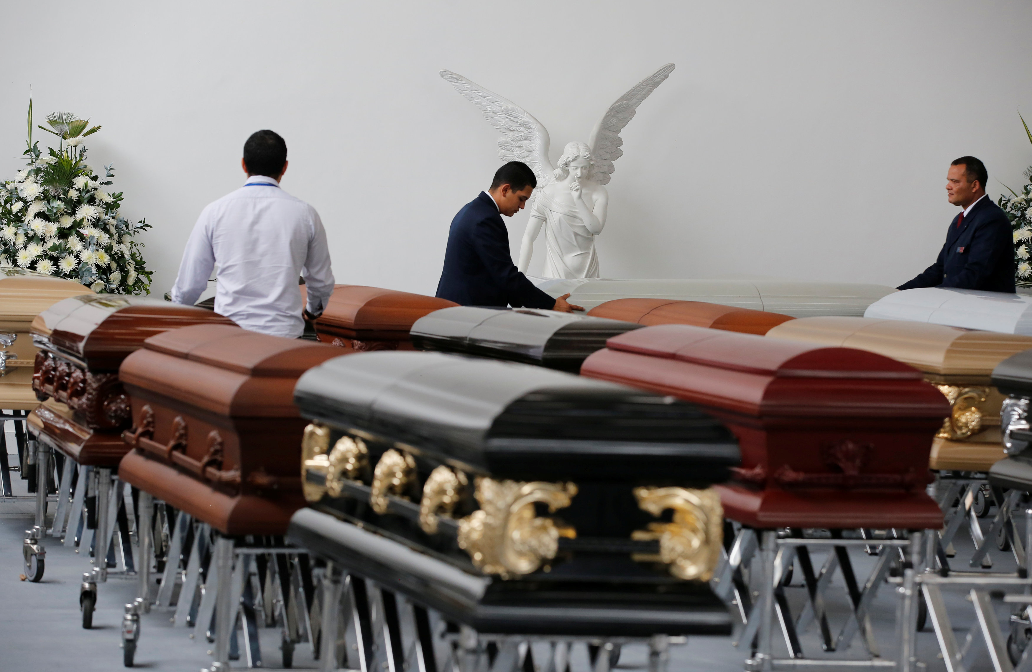 Funeral workers arrange coffins holding the remains of the victims who died in an accident of a plane that crashed into the Colombian jungle with Brazilian soccer team Chapecoense onboard, in Medellin, Colombia December 1, 2016. REUTERS/Jaime Saldarriaga TPX IMAGES OF THE DAY