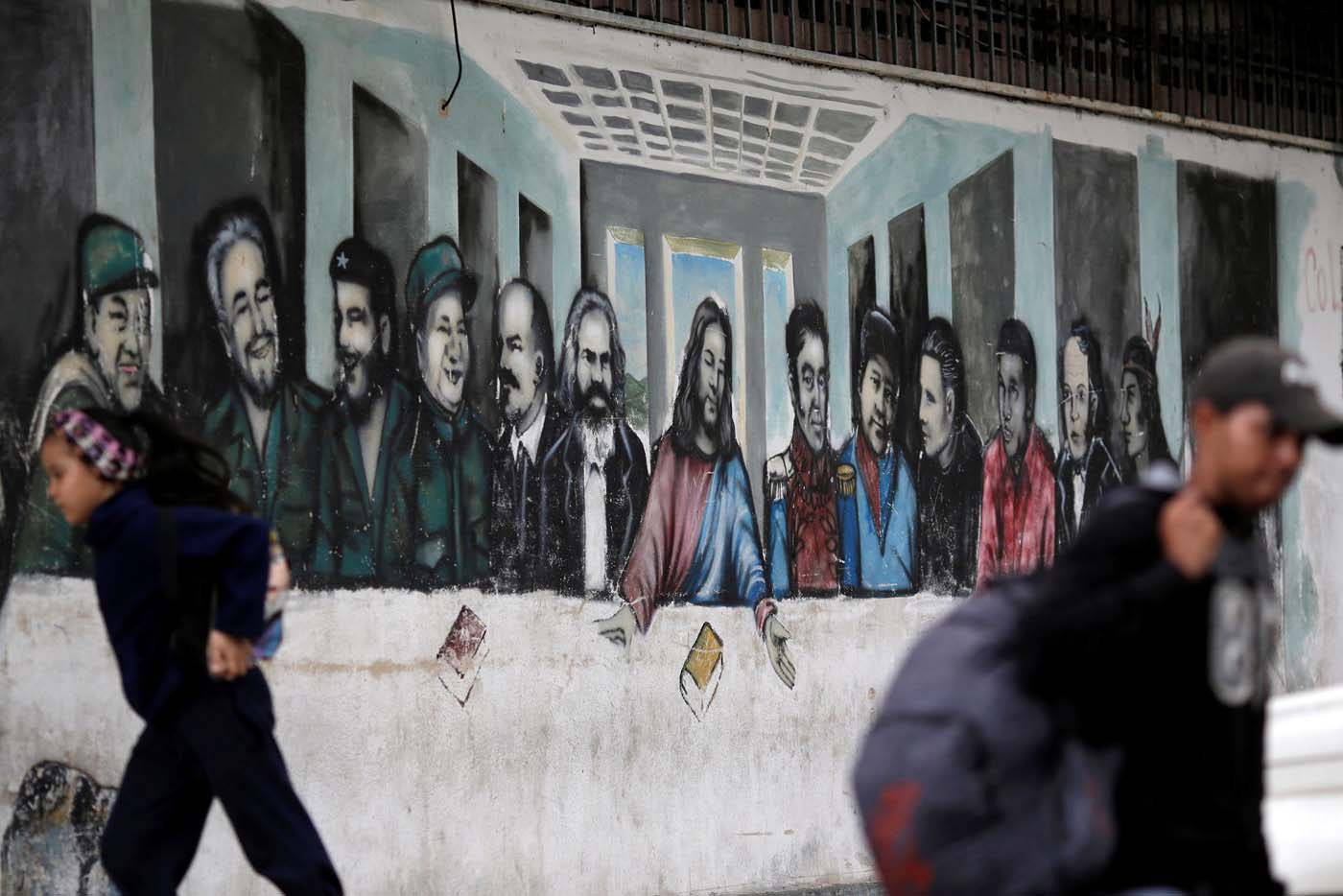 People pass next to a mural depicting the communist leaders at the 23 Enero neighbourhood in Caracas, Venezuela, November 30, 2016. REUTERS/Ueslei Marcelino