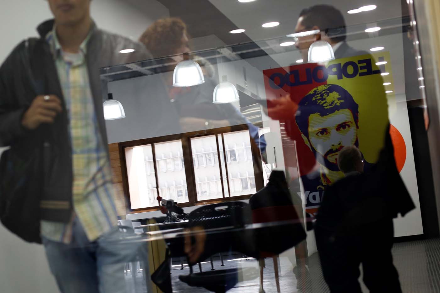 People walk next to an reflected image depicting the jailed opposition leader Leopoldo Lopez at the office of the party Popular Will (Voluntad Popular) in Caracas, Venezuela January 18, 2017. Picture taken January 18, 2017. REUTERS/Carlos Garcia Rawlins