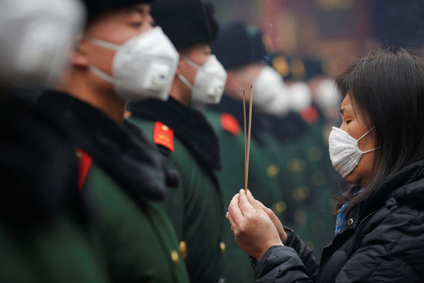 A woman holding incense sticks and paramilitary policemen wear face masks as people gather at Yonghegong Lama Temple to pray for good fortune on the first day of the Lunar New Year of the Rooster in Beijing, China January 28, 2017. REUTERS/Damir Sagolj TPX IMAGES OF THE DAY
