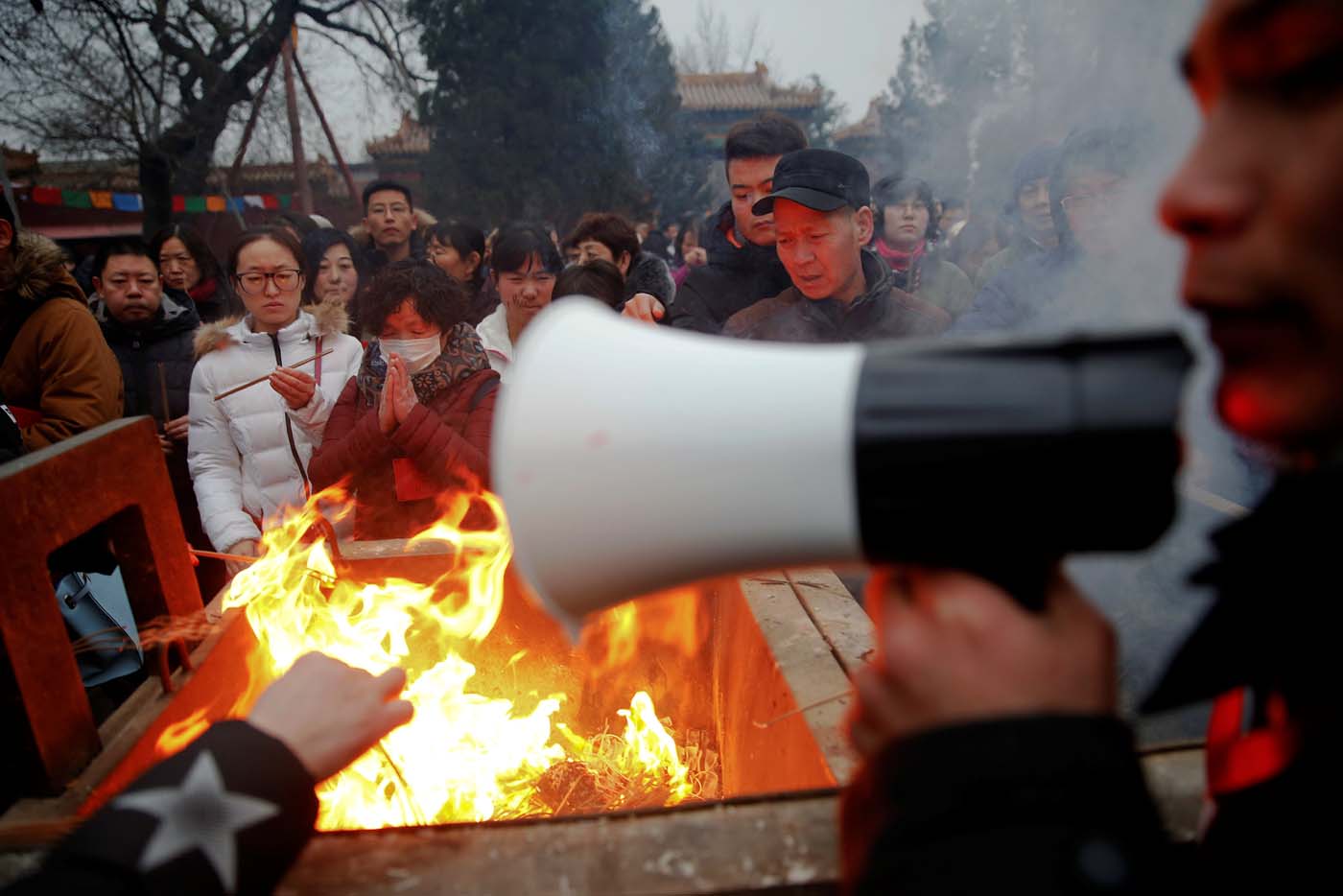 A man uses a megaphone to give instructions as people burn incense sticks and pray for good fortune at Yonghegong Lama Temple on the first day of the Lunar New Year of the Rooster in Beijing, China January 28, 2017. REUTERS/Damir Sagolj