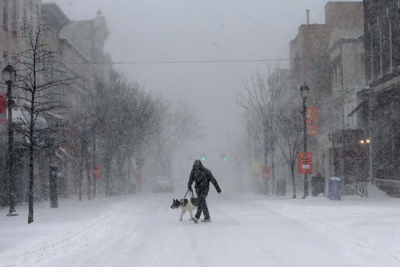 A man walks his dog in heavy falling snow on Main Street in the village of Nyack, New York, a suburb north of New York City, U.S., February 9, 2017. REUTERS/Mike Segar