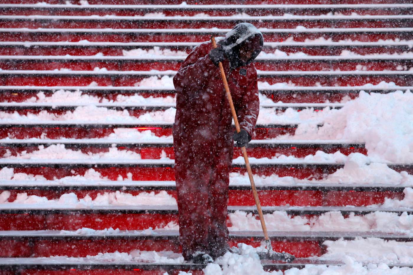 A worker attempts to clear steps in Times Square as snow falls in Manhattan, New York, U.S. February 9, 2017. REUTERS/Andrew Kelly
