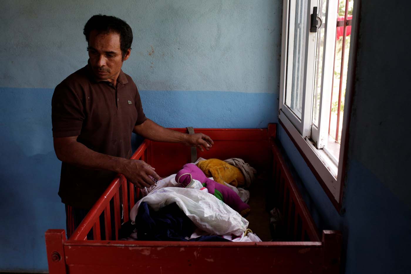 Tulio Medina, father of Eliannys Vivas, who died from diphtheria, puts clothes on a cot at his home in Pariaguan, Venezuela January 26, 2017. Picture taken January 26, 2017. REUTERS/Marco Bello
