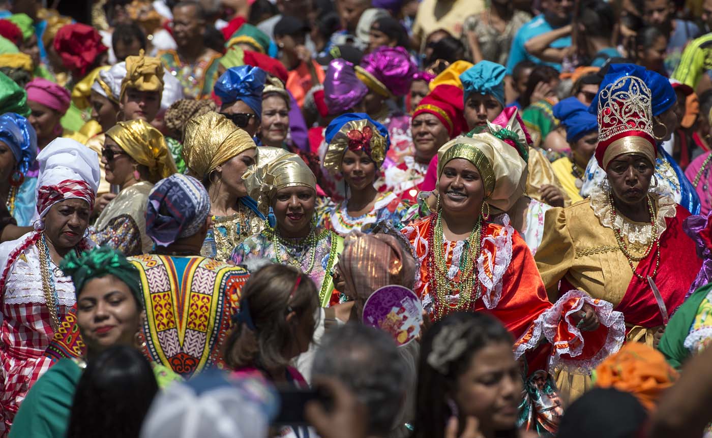 Women dressed as "madamas" dance as they take part in a parade during the Carnival in El Callao, Bolivar state, Venezuela on February 26, 2017.  El Callao's carnival was recently named Unesco's Intangible Cultural Heritage of Humanity and is led by the madamas, the pillars of Callaoense identity representing Antillean matrons considered the communicators of values, who dance and wear colourful dresses. / AFP PHOTO / JUAN BARRETO