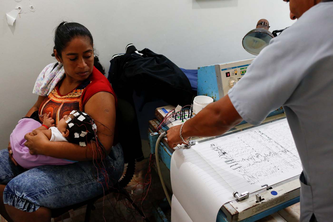 Iberis Vargas (L), holds her 7-month-old daughter, Geovelis Ramos, a neurological patient being treated with anticonvulsants, during an electroencephalogram in a clinic in La Guaira, Venezuela February 4, 2017. REUTERS/Carlos Garcia Rawlins    SEARCH "EPILEPSY CARACAS" FOR THIS STORY. SEARCH "WIDER IMAGE" FOR ALL STORIES.