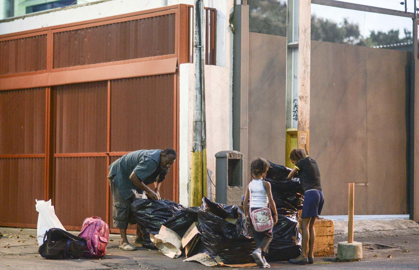  Un hombre y dos niñas escarban en la basura en Caracas  AFP PHOTO / JUAN BARRETO  