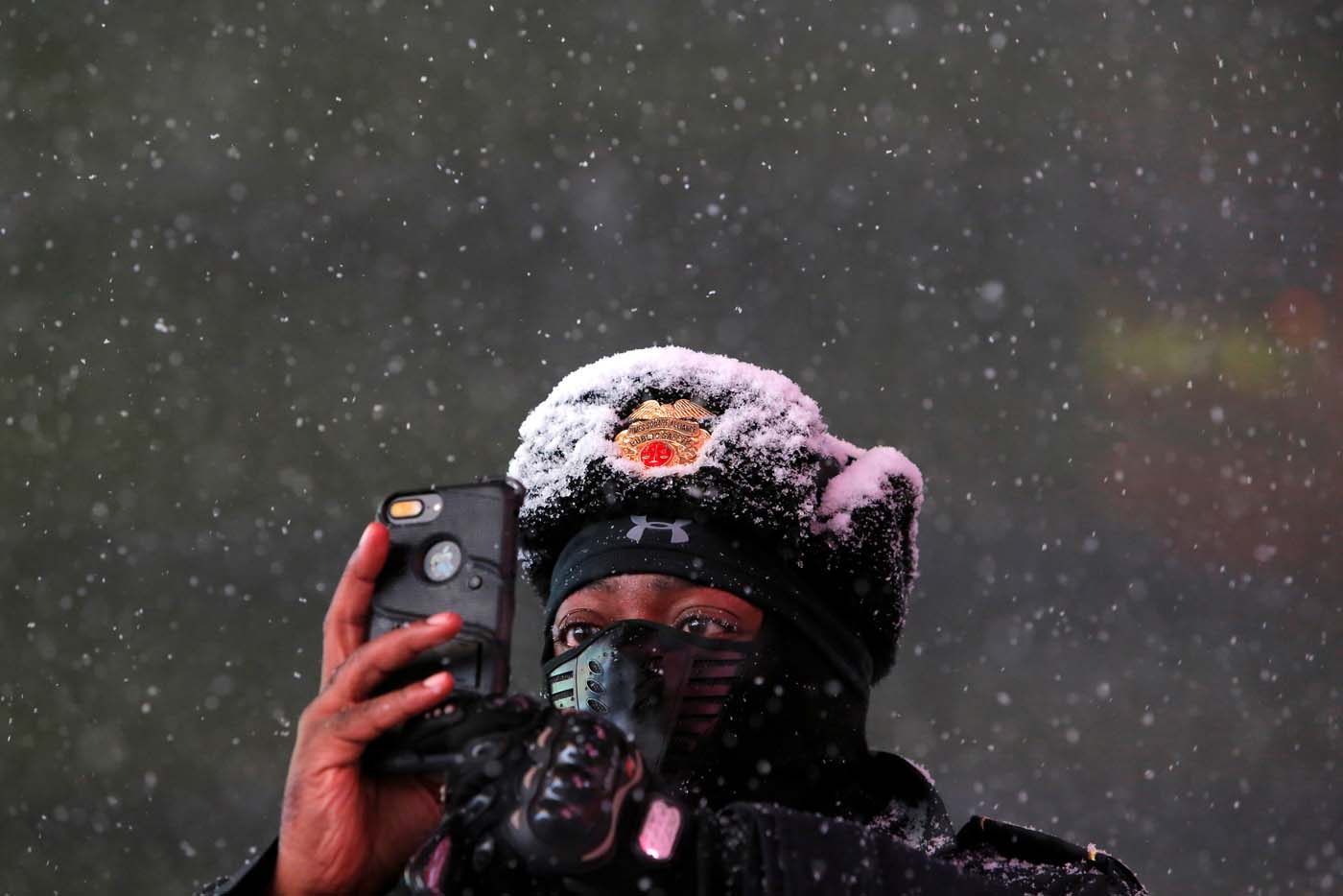 Times Square Public Safety Sergeant Baldwin Davis captures falling snow with his cellular device in Times Square in Manhattan, New York, U.S., March 14, 2017. REUTERS/Andrew Kelly