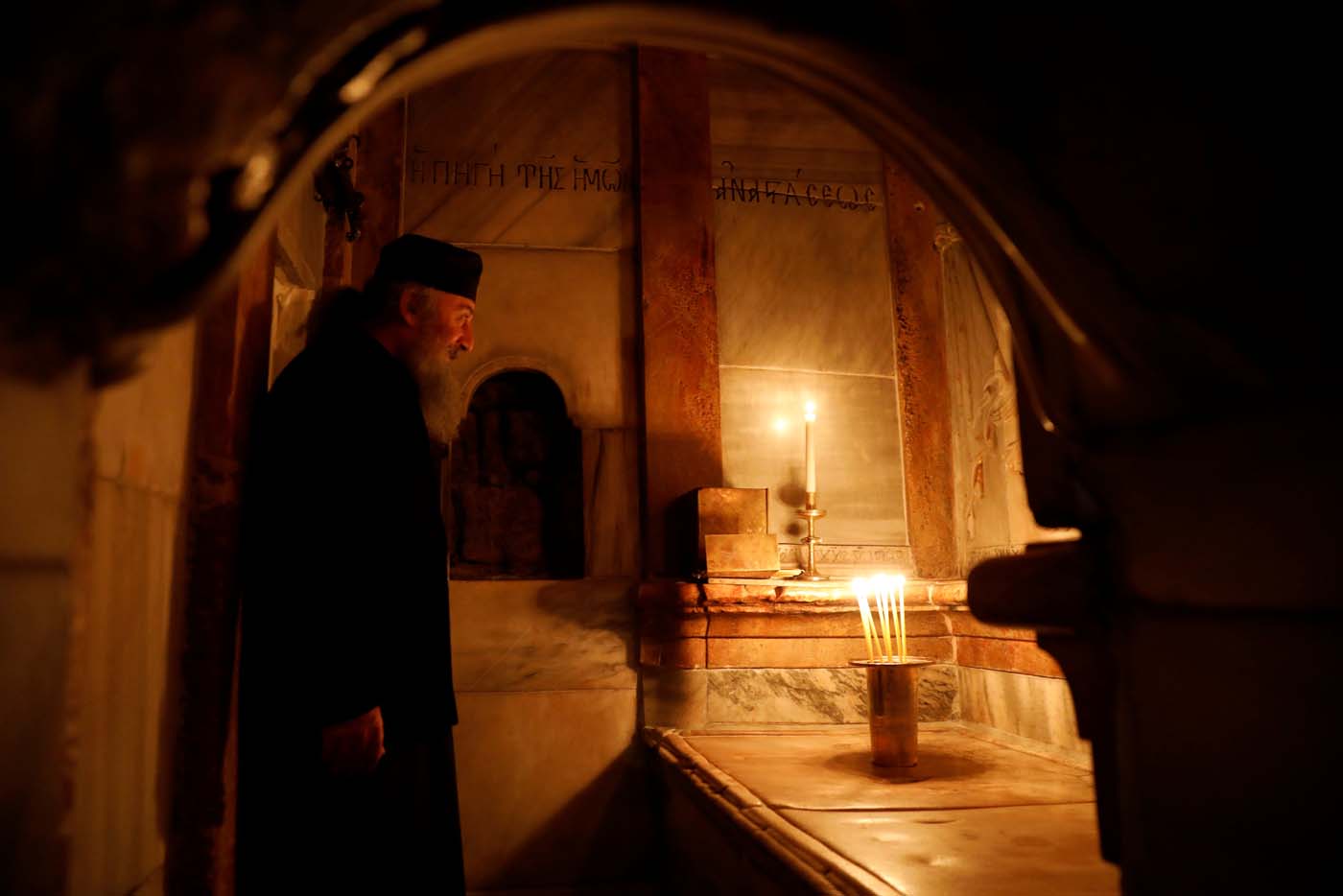 A Greek Orthodox priest stands inside the newly restored Edicule, the ancient structure housing the tomb (seen in front of him), which according to Christian belief is where Jesus's body was anointed and buried, at the Church of the Holy Sepulchre in Jerusalem's Old City March 20, 2017. REUTERS/Ronen Zvulun