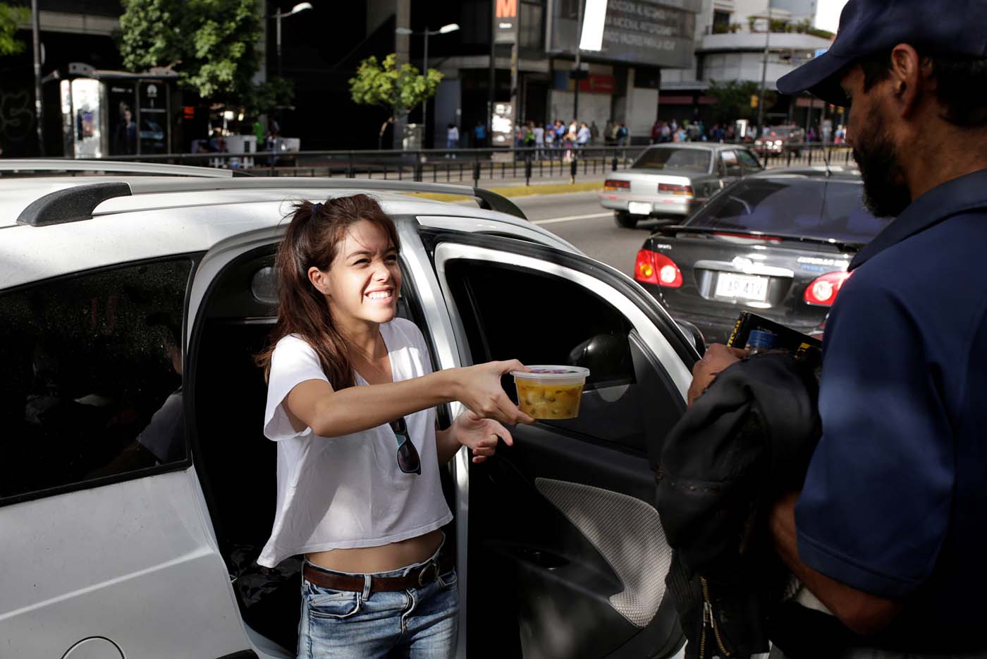 Mariana Zuniga (L), volunteer of Make The Difference (Haz La Diferencia) charity initiative, gives a cup of soup to a man in a street of Caracas, Venezuela March 5, 2017. Picture taken March 5, 2017. REUTERS/Marco Bello