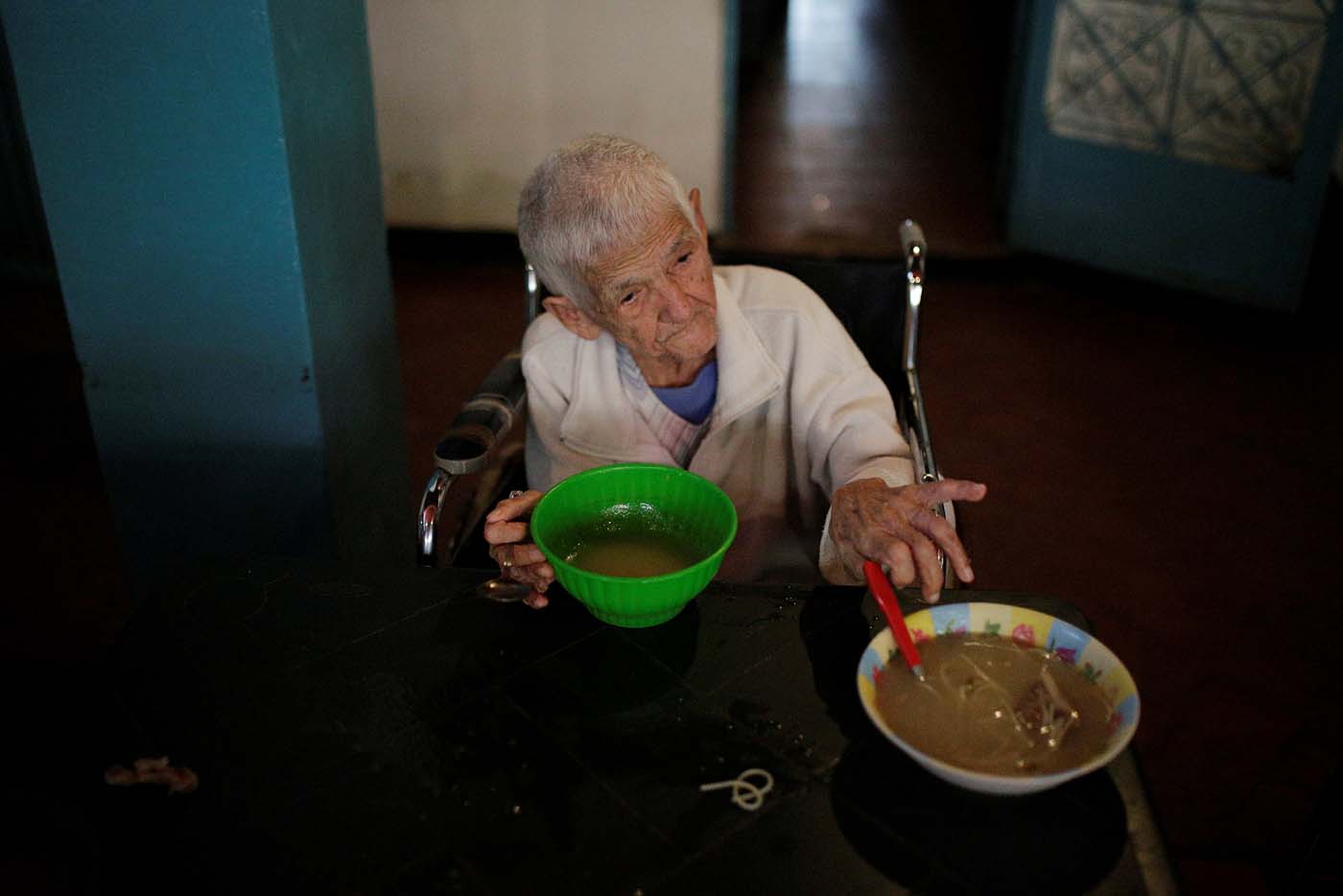 A woman grabs a bowl of soup donated by La Sibilla restaurant, member of the "Full Stomach, Happy Heart" (Barriga llena, corazon contento) charity, at the Mother Teresa of Calcutta nursing home, in Caracas, Venezuela February 23, 2017. Picture taken February 23, 2017. REUTERS/Marco Bello