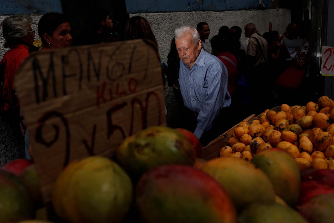 A man walks past people queueing to try and buy food outside a supermarket in Caracas, Venezuela May 23, 2016. REUTERS/Carlos Garcia Rawlins SEARCH "GARCIA QUEUEING" FOR THIS STORY. SEARCH "WIDER IMAGE" FOR ALL STORIES.